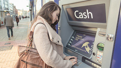 A lady withdraws money from a cashpoint machine. 